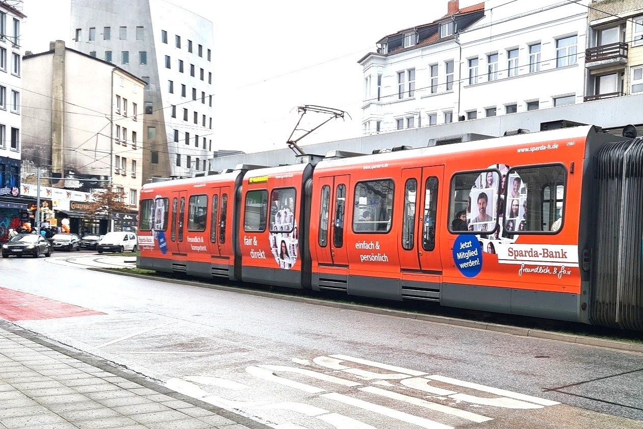 Eine rote ganzgestaltete Stadtbahn fährt durch die Innenstadt von Hannover.